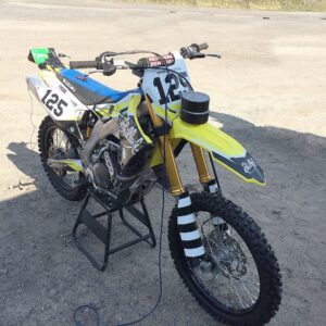 A yellow and blue Suzuki RM-Z450 2018 dirt bike on sandy terrain, perfect for "dirt bike sound effects library" needs.