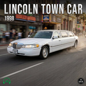 White 1998 Lincoln Town Car stretch limousine drives down a city street past blurred buildings.
