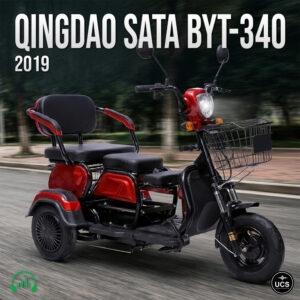 Red Qingdao Sata BYT-340 2019 power mobility wheelchair scooter with two seats, basket, and headlight travels on blurred road.