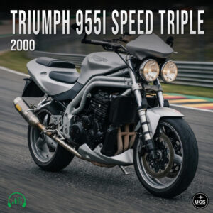 Silver 2000 Triumph 955i Speed Triple streetfighter muscle bike with dual round headlamps leans into a paved racetrack bend.